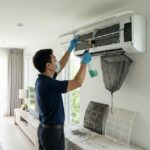 Serwisant wykonuje czyszczenie klimatyzacji w budynku mieszkalnym